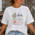 White t-shirt with watercolor cross and pink floral graphic, script text reads Give Thanks for what was, Believe in what is, Hope for what's to come